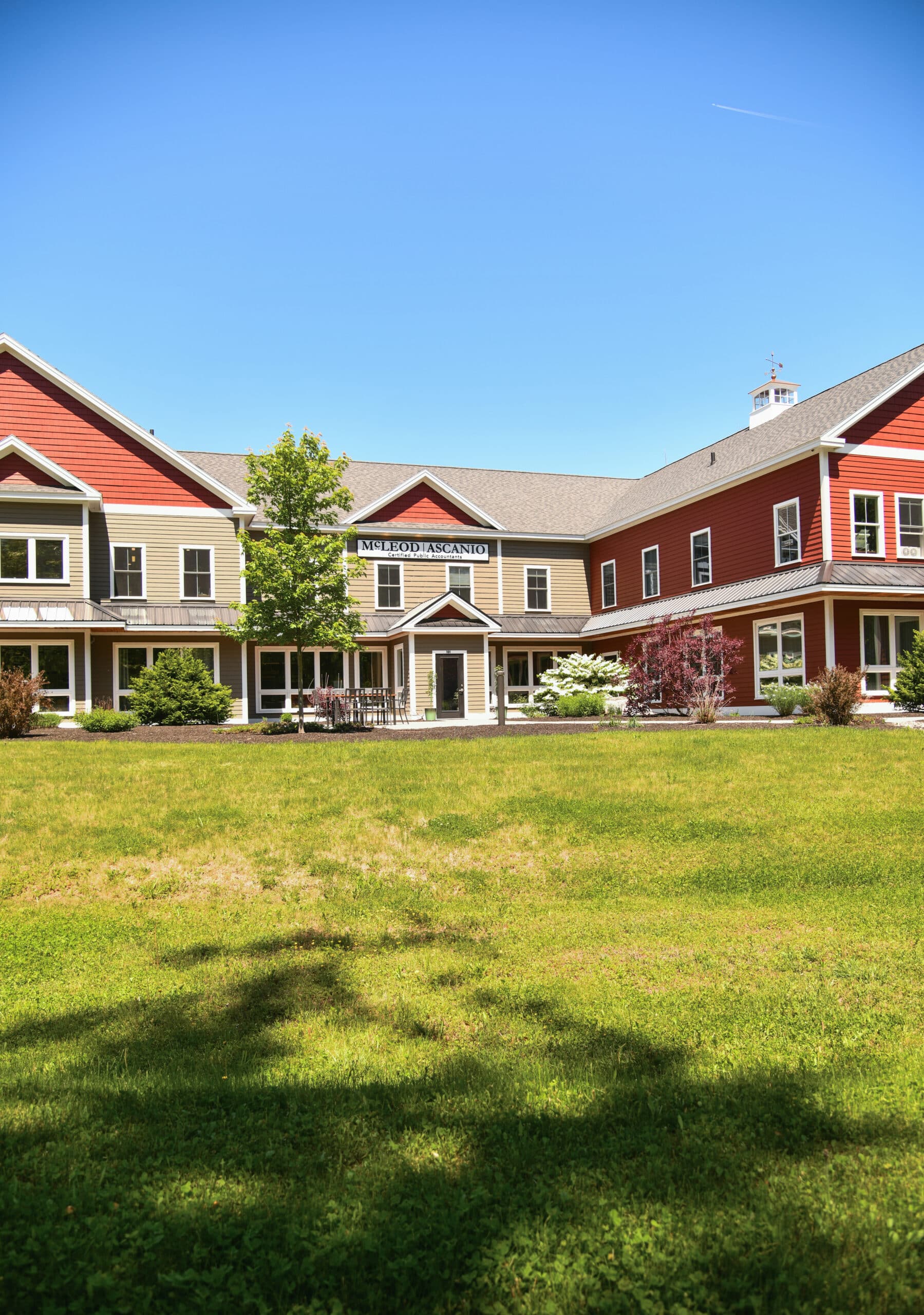 Exterior of a red-and-tan office building labeled “McLeod Ascanio Certified Public Accountants,” with a lawn and clear blue sky